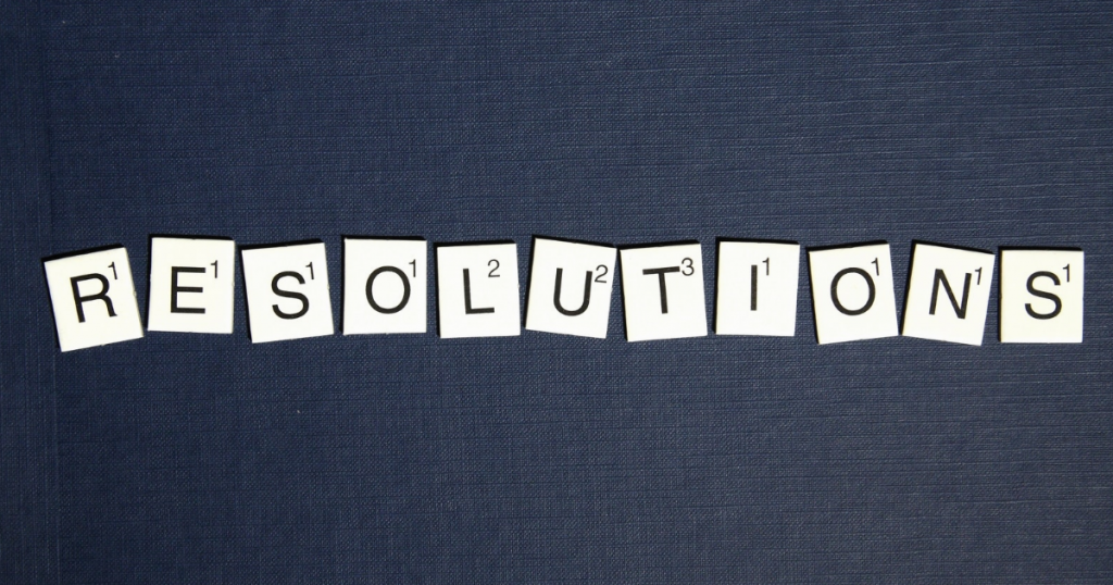 on a blue jean background, the word resolutions is spelled out in scrabble tiles