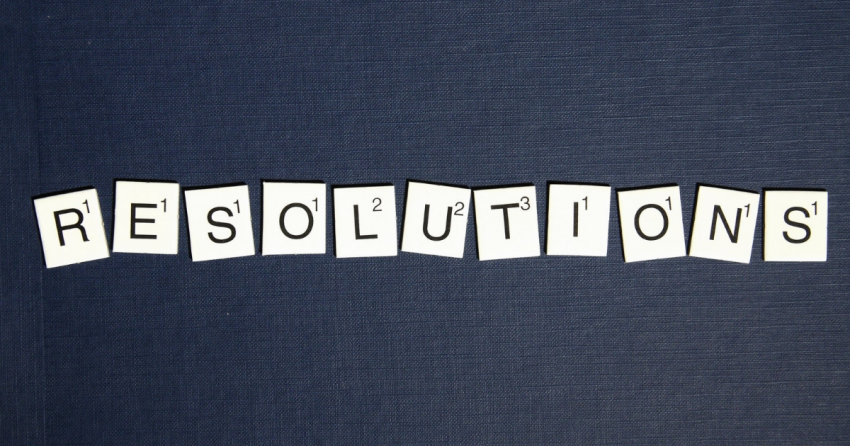 on a blue jean background, the word resolutions is spelled out in scrabble tiles